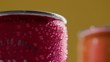 Cerca-De-Gotas-De-Condensación-En-Latas-Giratorias-De-Cerveza-Fría-O-Refrescos-Para-Llevar-Contra-Fondo-Amarillo